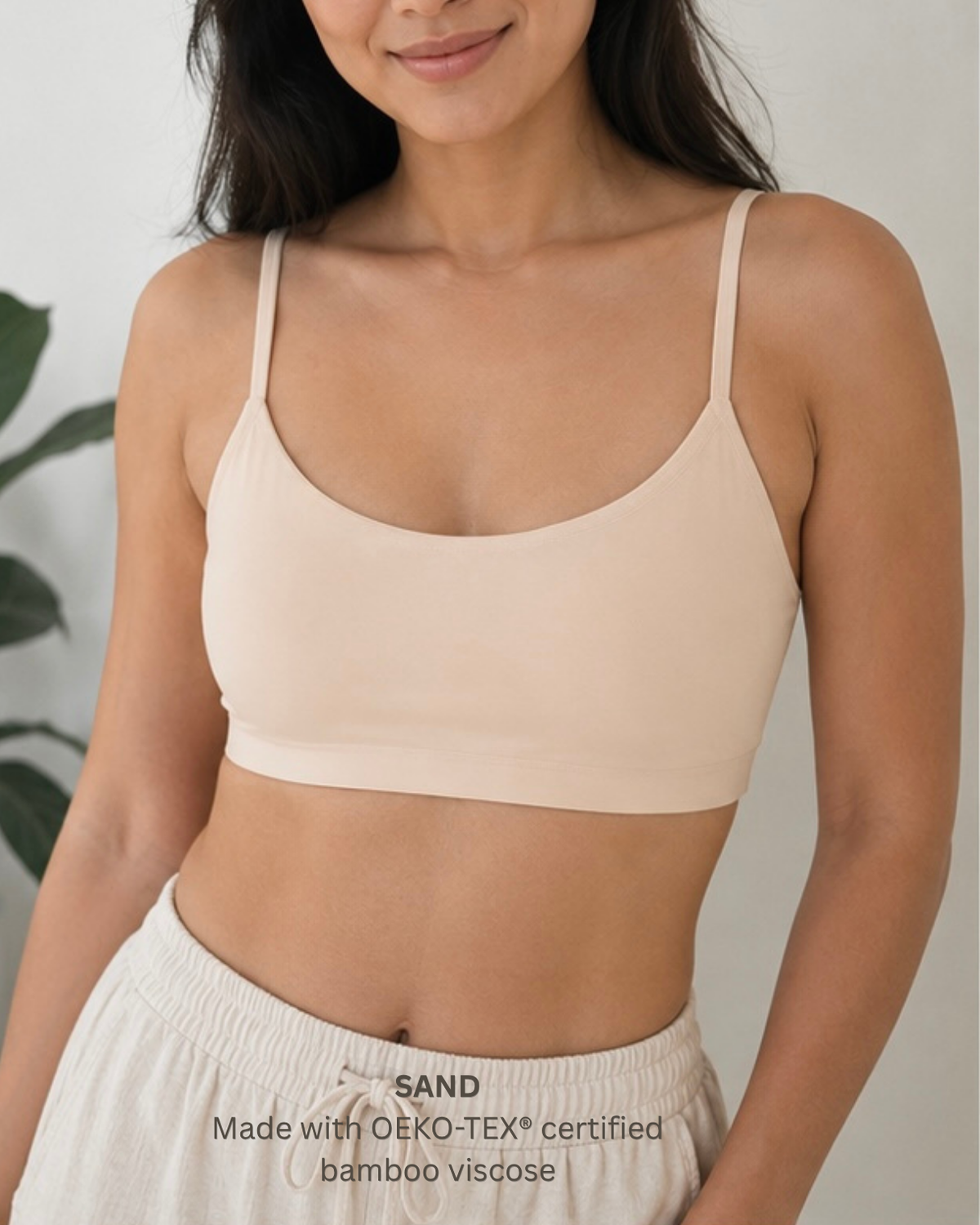 A woman wearing a light beige spaghetti-strap bralette and matching light beige bottoms.