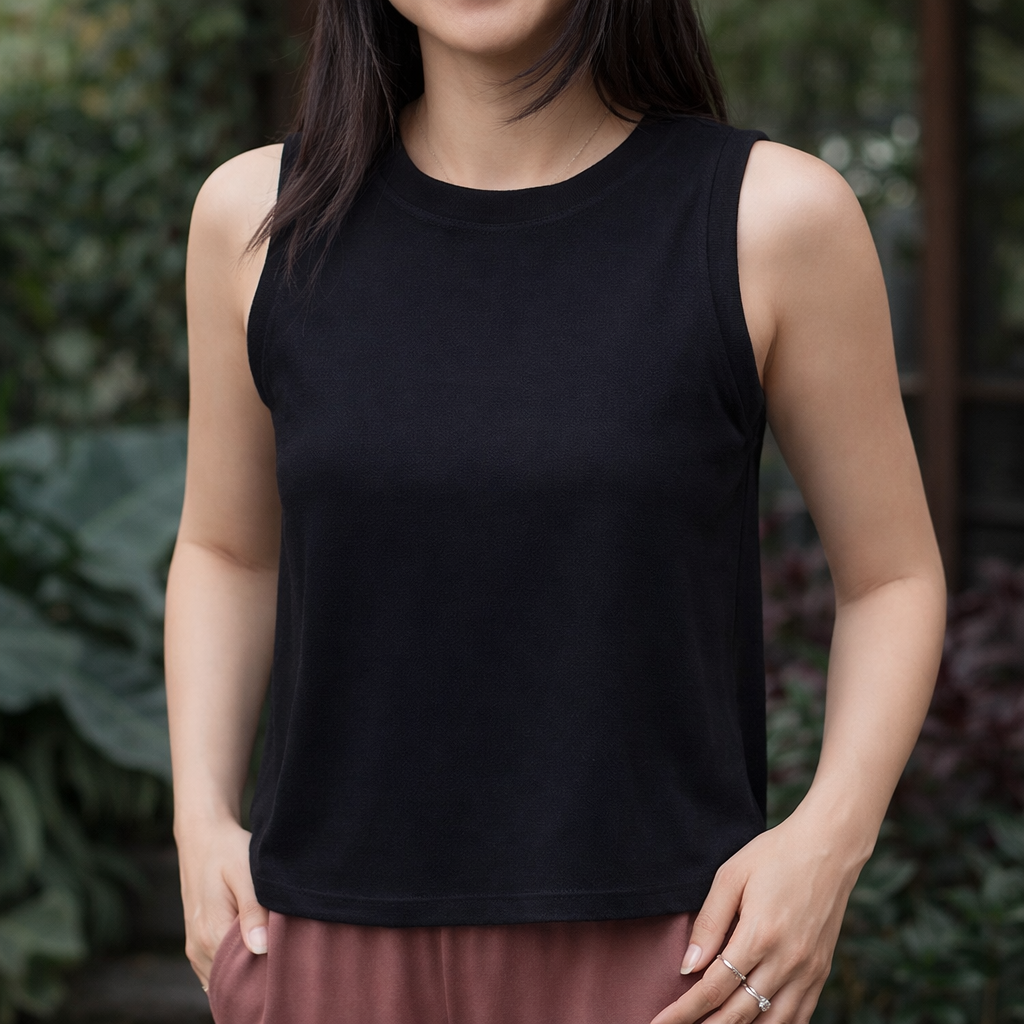 Person wearing a black sleeveless top with a blurred green background